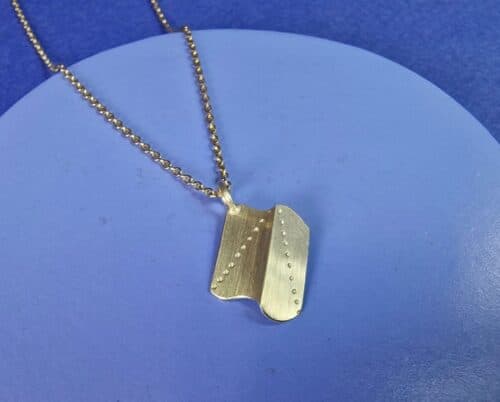 Geelgouden hanger uit Vouwen serie, amorfe vorm met vouw en stip patroon. Uit het Oogst atelier.