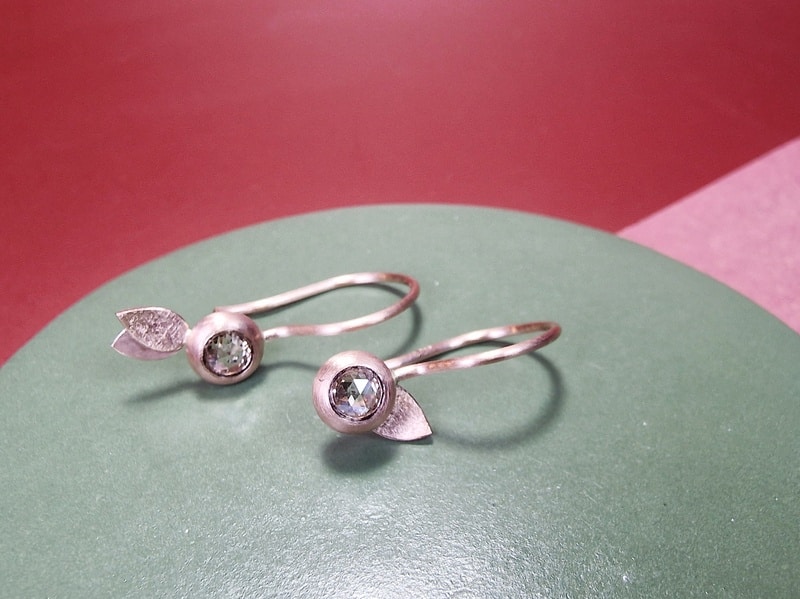 Rose gold earrings with rose cut diamonds from the 'Leaves' series. With an elegant curly hook. Playful asymmetrical pair, handmade at the Oogst goldsmith studio.