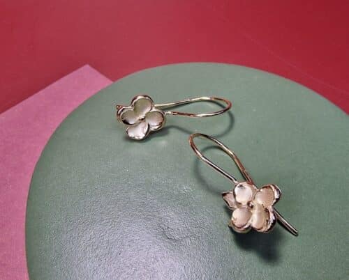 Tijdloze geelgouden oorsieraden met bloesems met een elegante krul. One-of-a-kind asymmetrisch paar, ontwerp uit het Oogst goudsmid atelier.